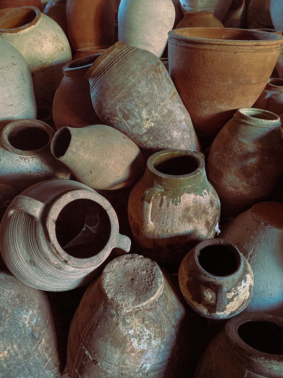 A store of antique terracotta pots and oil jars stacked together, awaiting rehoming
